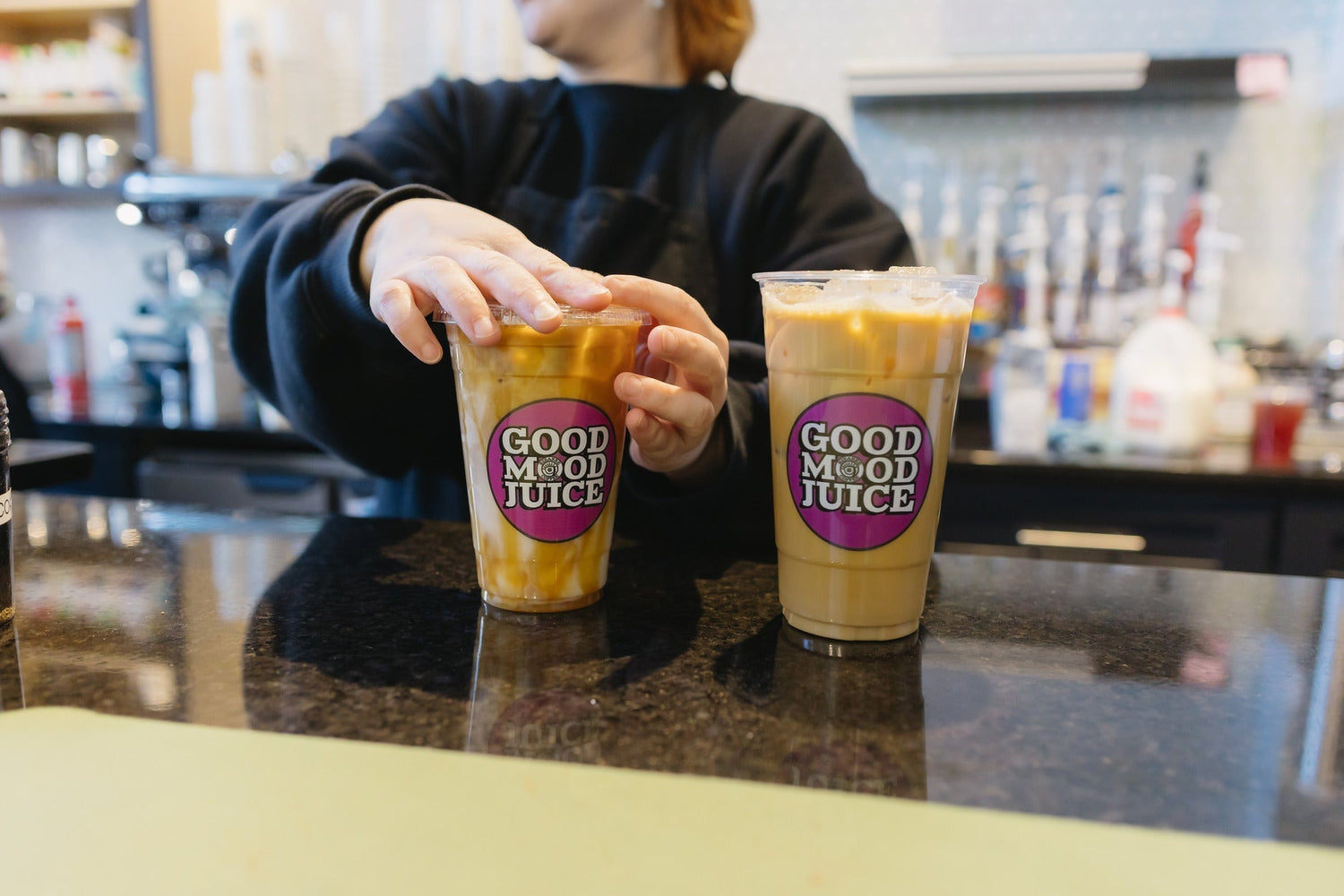 Barista at Bizarre Coffee serving iced lattes made with Brazil Medium Roast