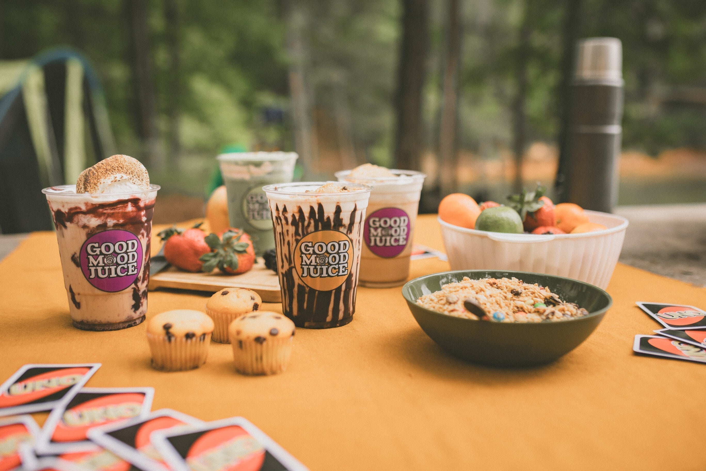 An ourdoor camping table with iced coffee drinks, a card game and snacks.