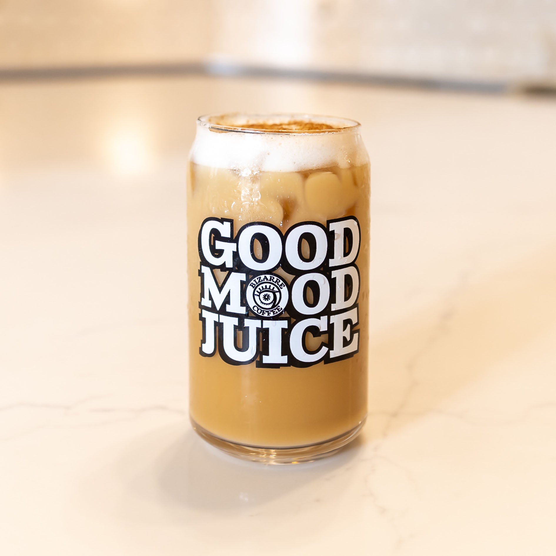 A glass cup that says Good Mood Juice with an iced latte inside.