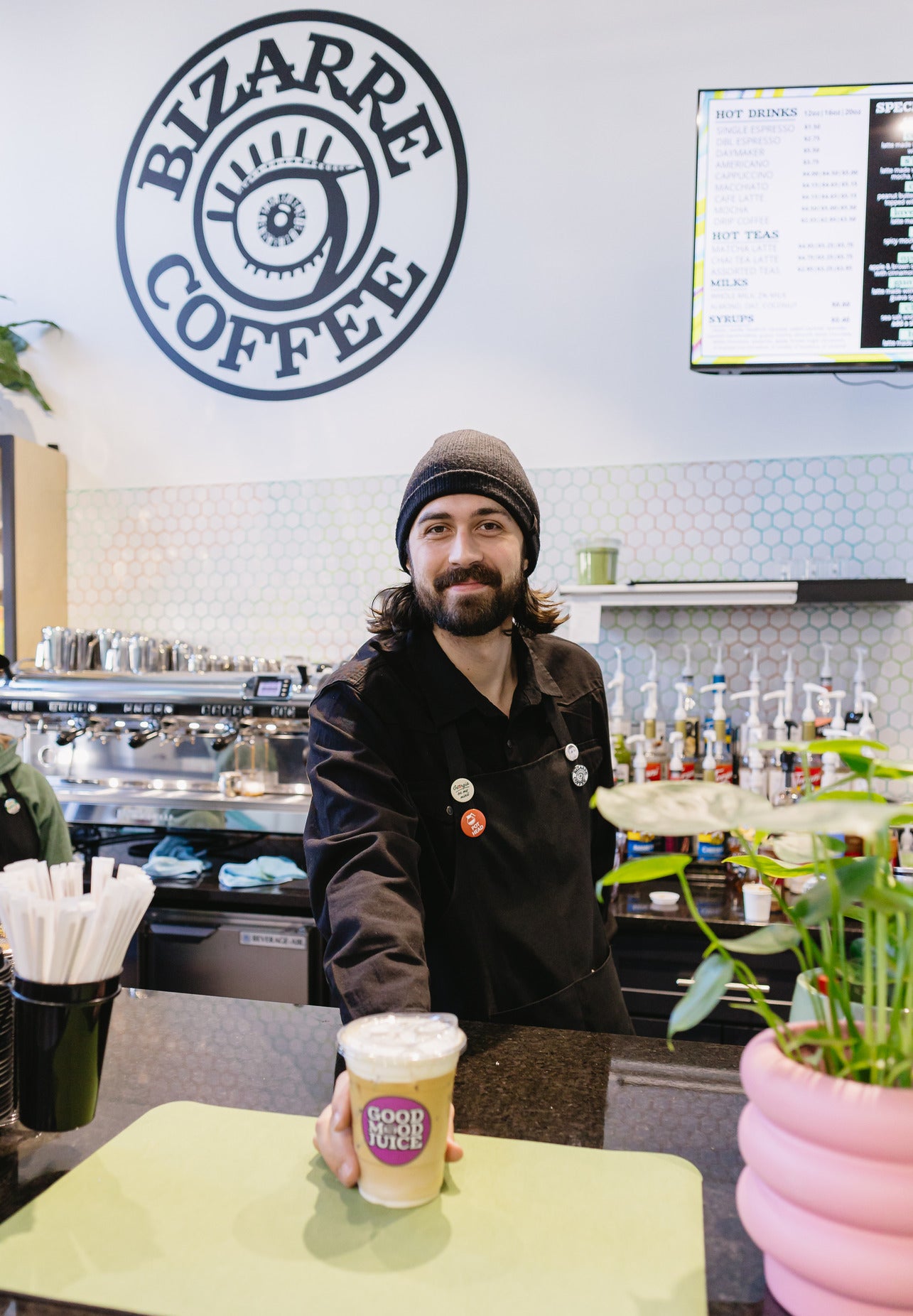 A barista handing a latte to a customer at a Bizarre coffee shop