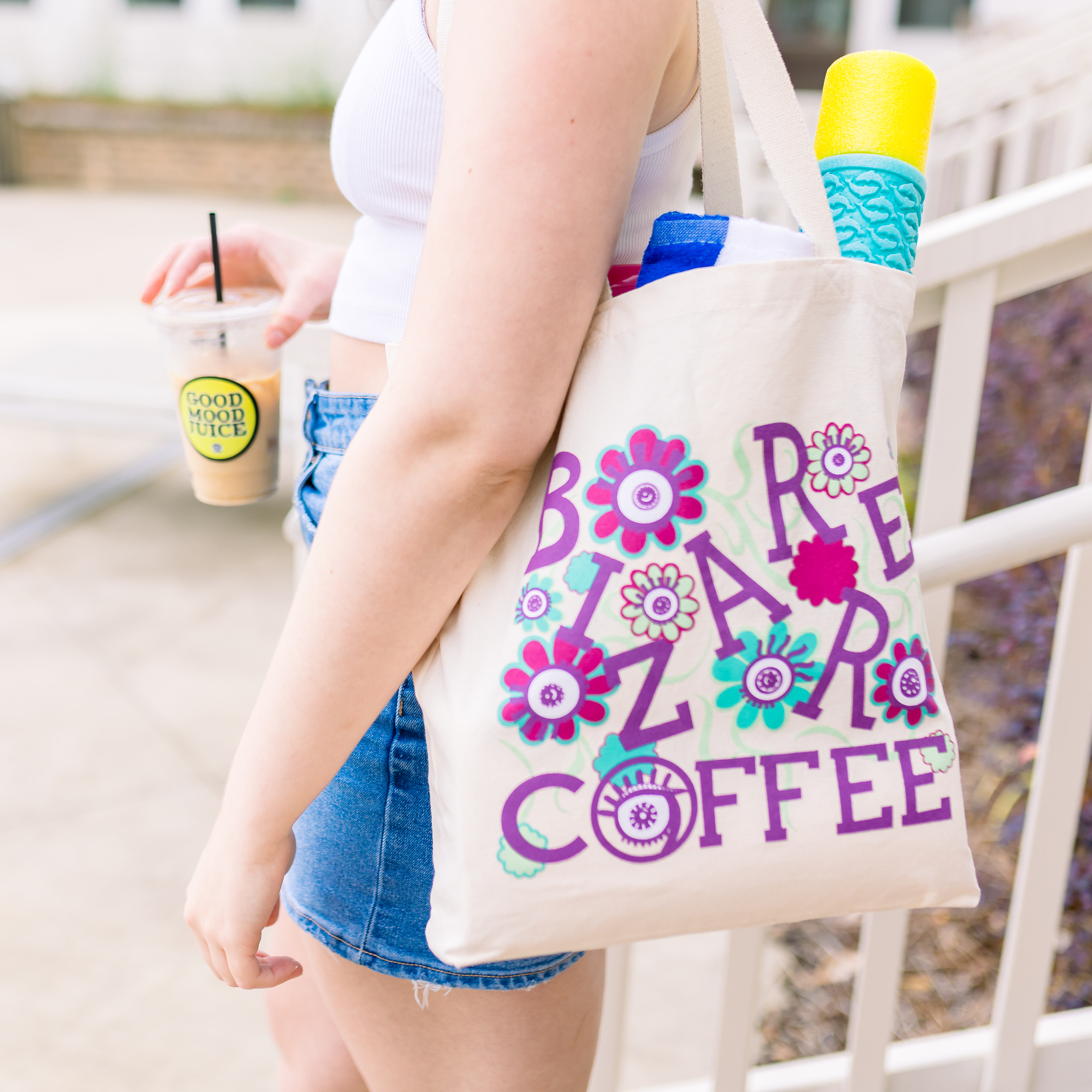 A canvas tote bag that says Bizarre Coffee in purple letters with flowers and eyes. 