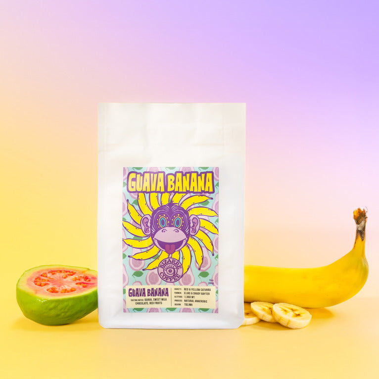 A bag of coffee with a guava fruit and banana on the sides.