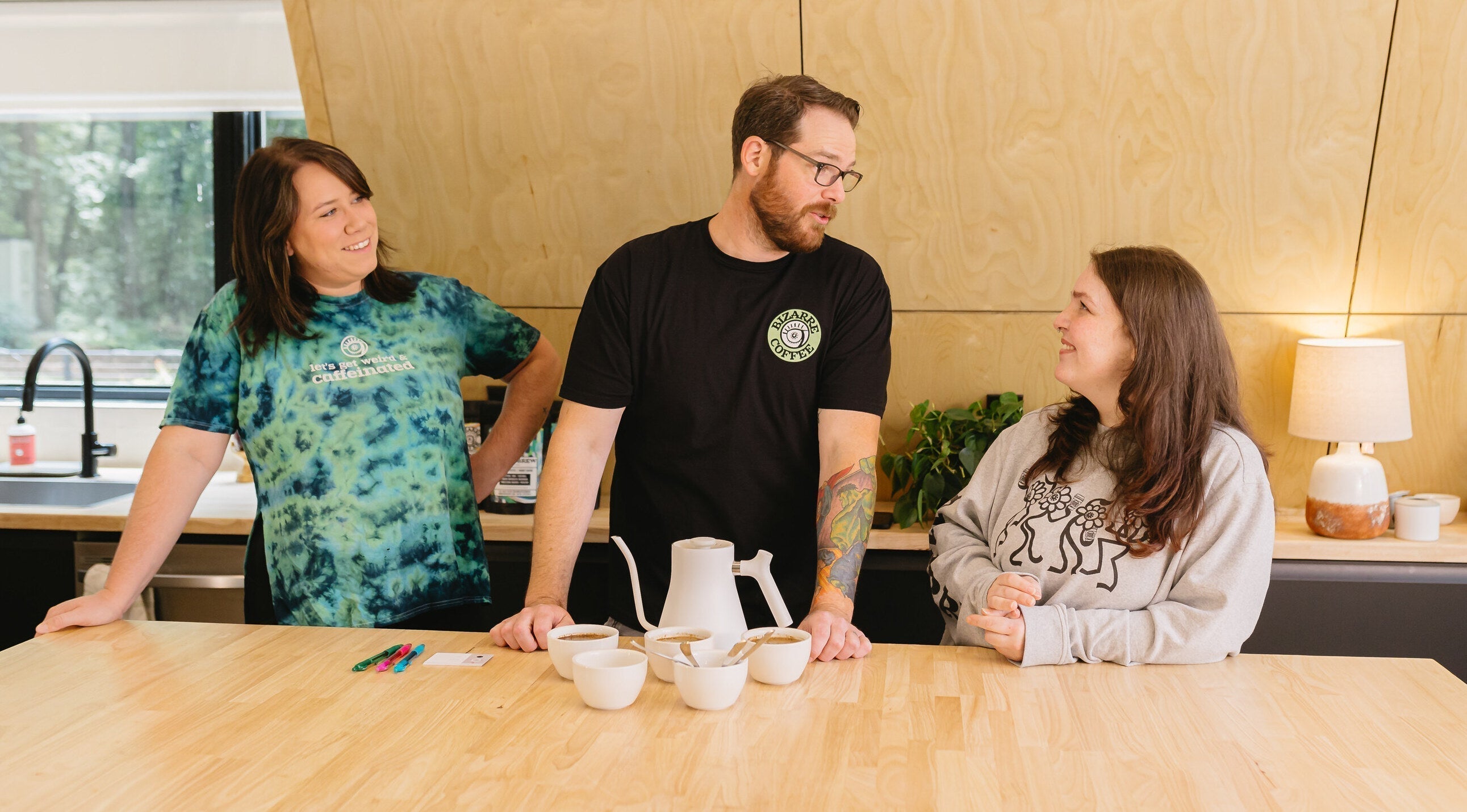 Three people getting ready to cup coffee.