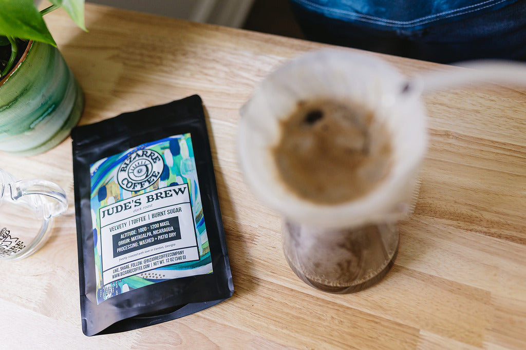 A bag of coffee beans next to a chemex pour over.