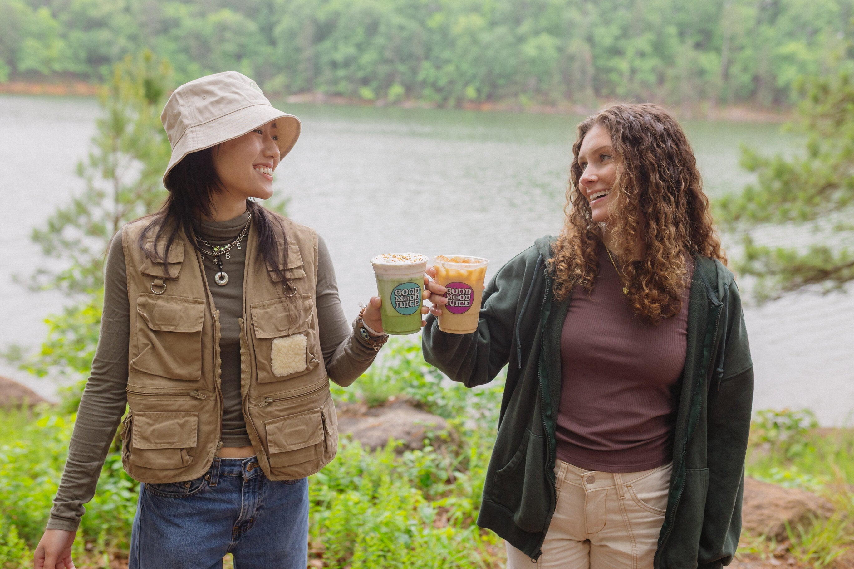 Women holding Iced Lattes in front of a lake