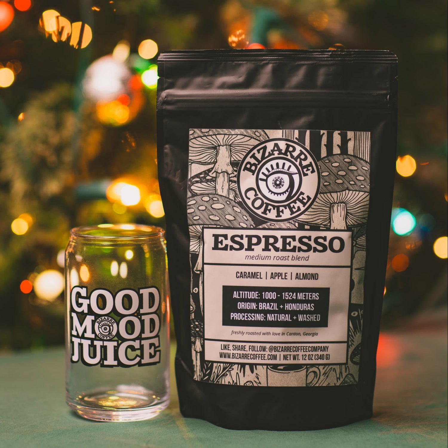 Bizarre Coffee Espresso package and 'Good Mood Juice' glass with a bag of Espresso Medium Roast Blend and a Christmas tree in the background
