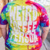 Person wearing a tie-dye t-shirt with text outdoors.