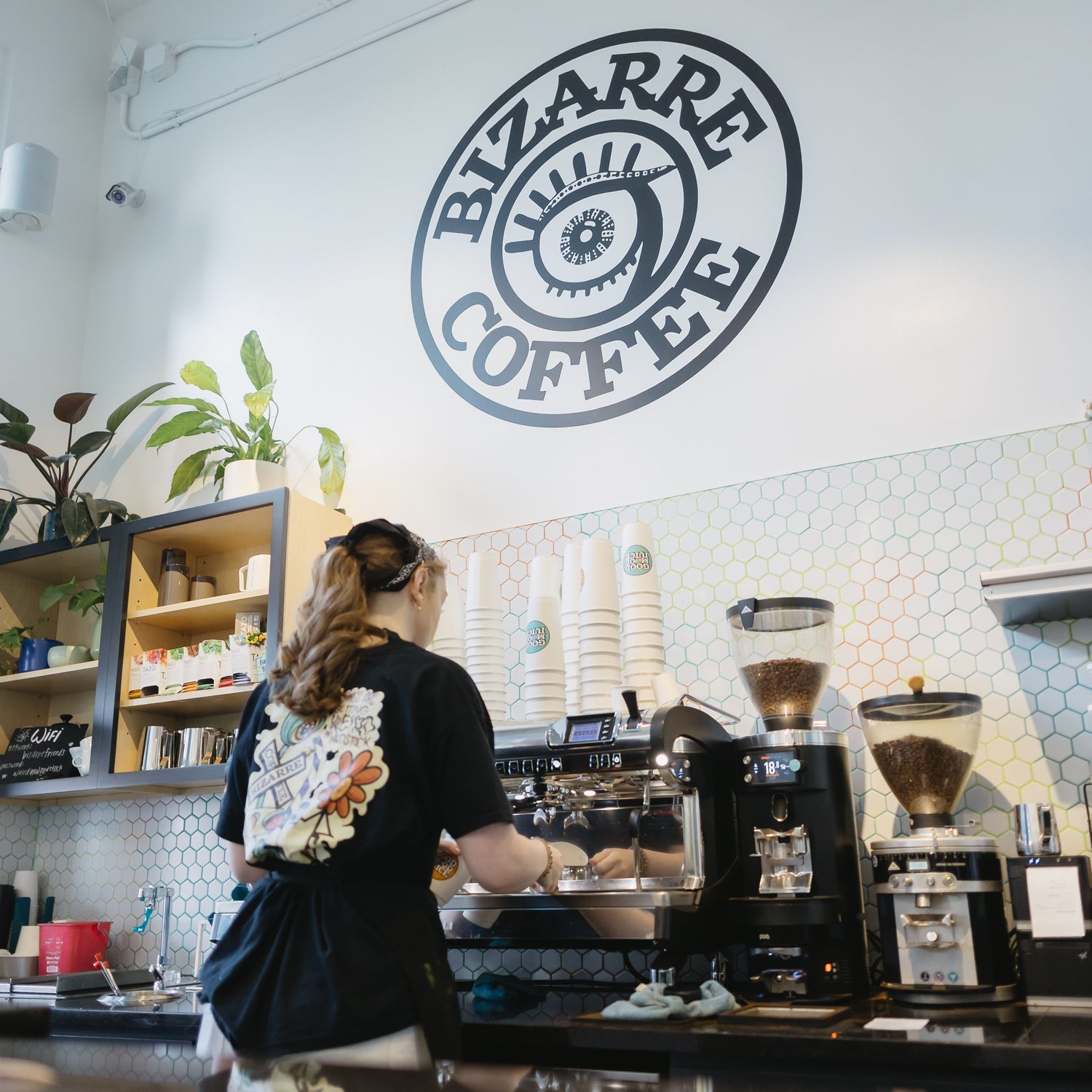 Person working behind a counter with 'Bizarre Coffee' logo on the wall.