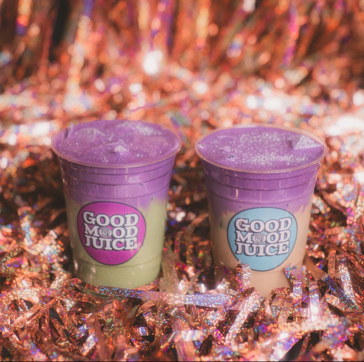 Two purple cups labeled 'Good Mood Juice' on a glittery background