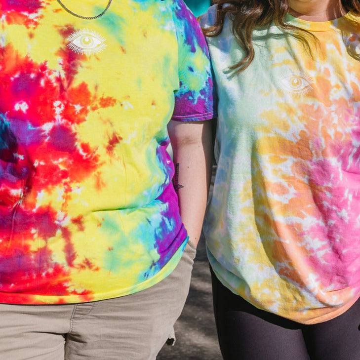 Two people wearing tie-dye shirts in vibrant colors.