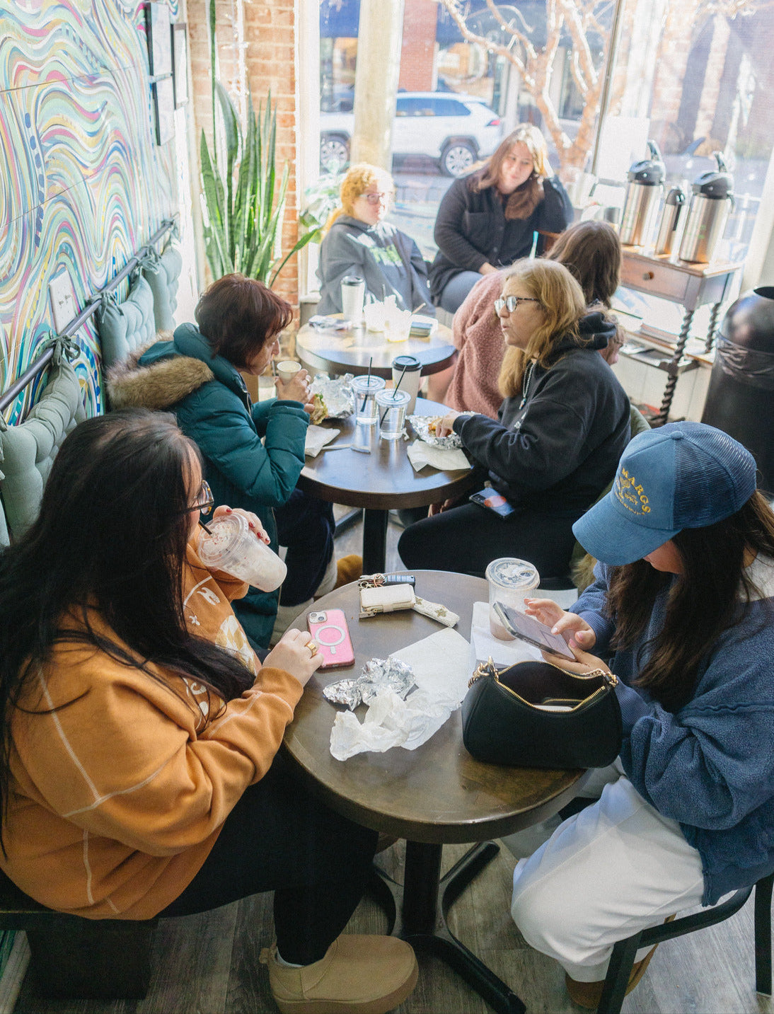 People sitting around a table in a cozy cafe with colorful walls and a window view.