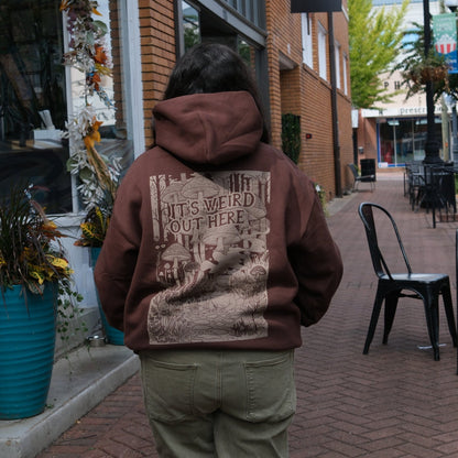 Person wearing a hoodie with a graphic design on a city street