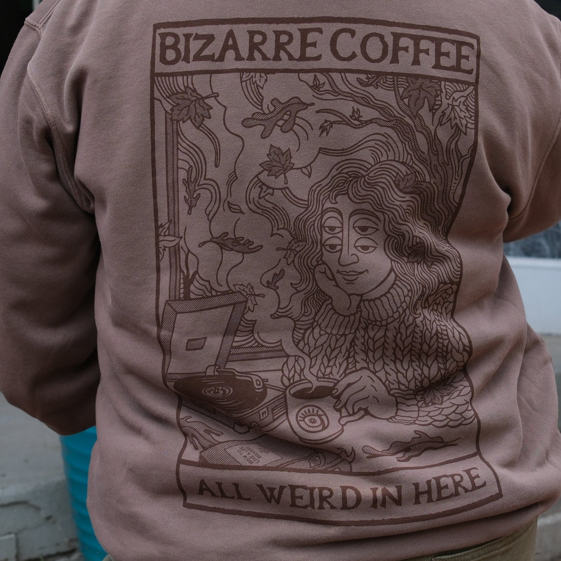 Person wearing a brown hoodie with a graphic design and text on the back.