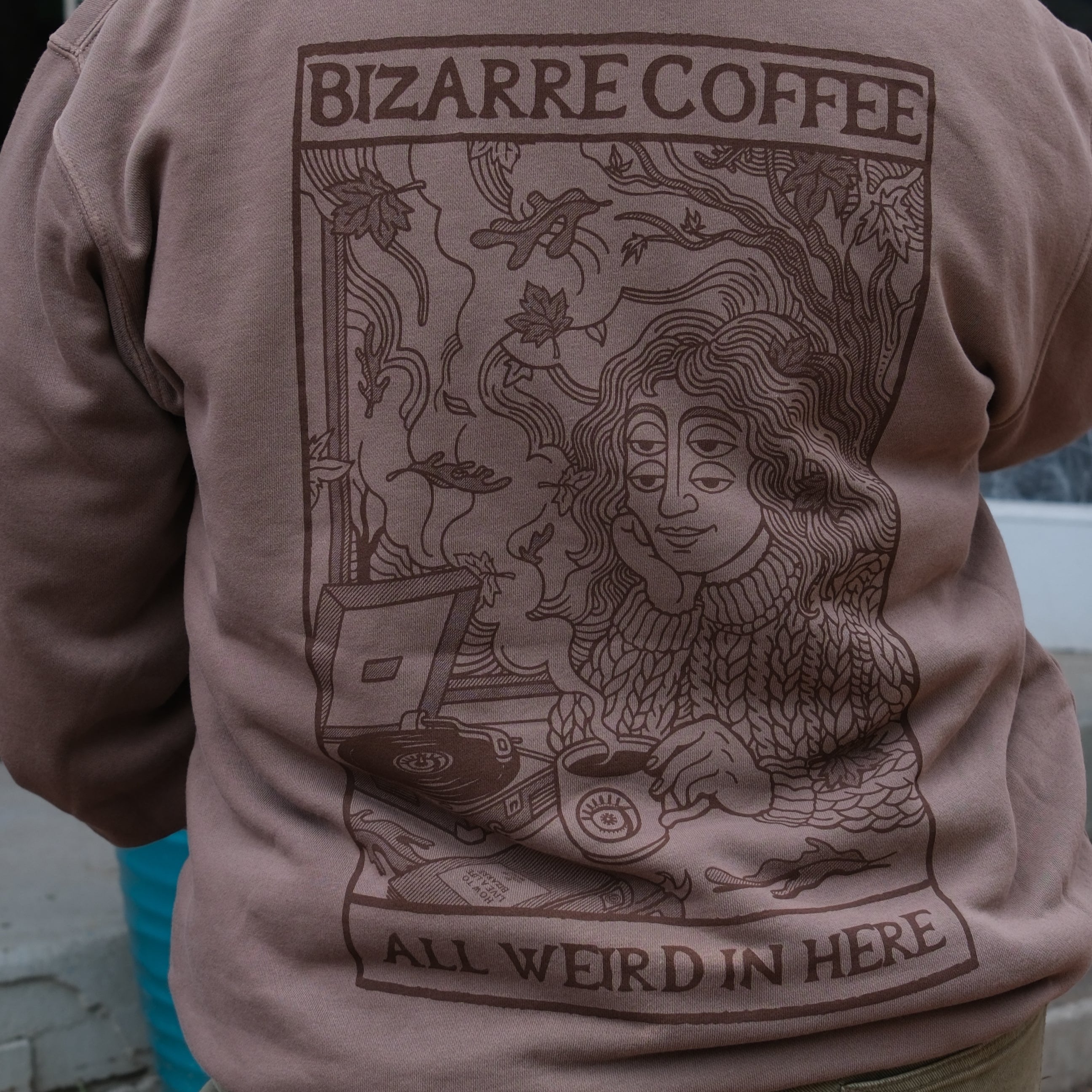 Person wearing a brown hoodie with a graphic design and text on the back.