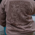 Person wearing a brown hoodie with a graphic design and text on the back.