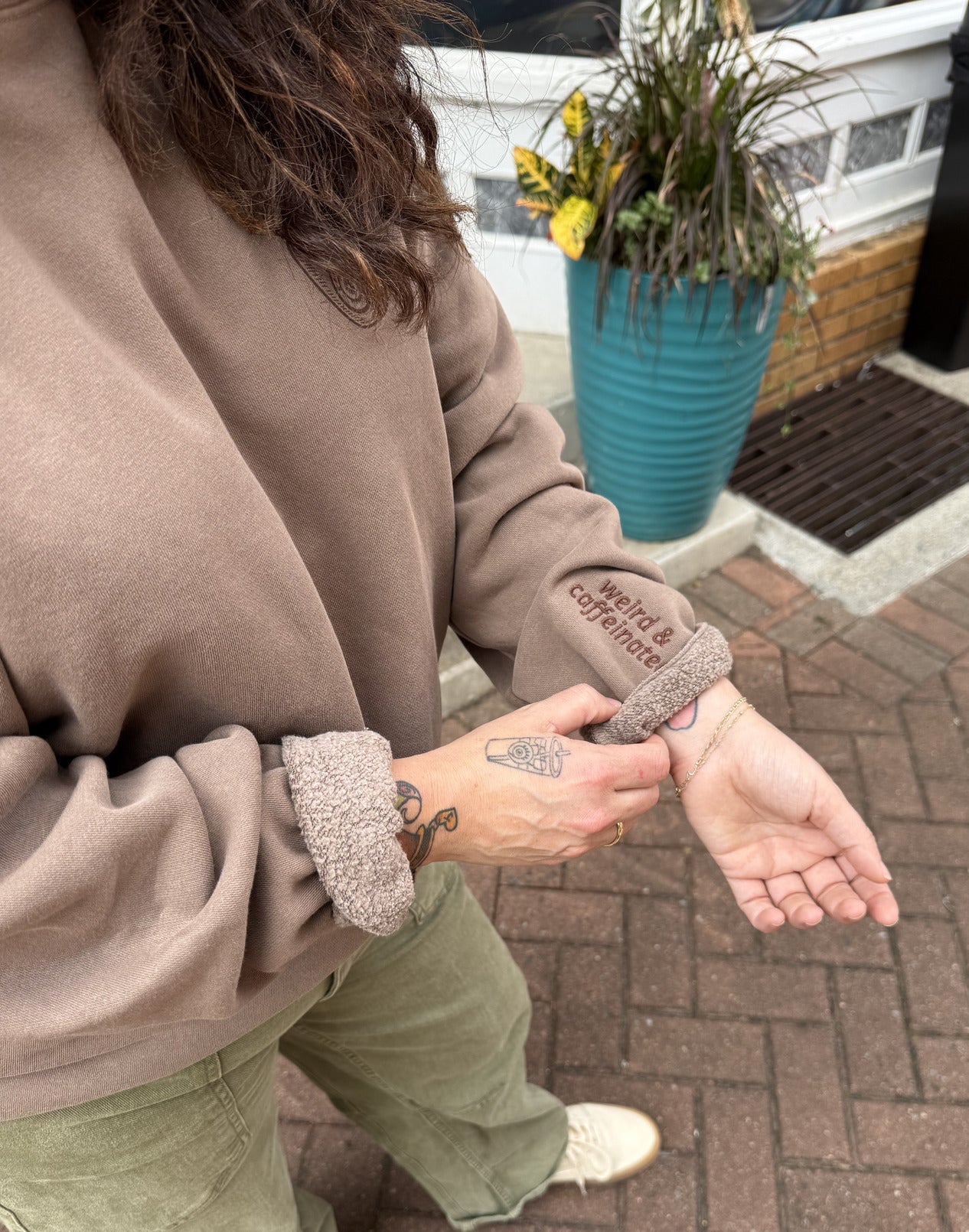 Person holding a sleeve showing embroidery detailing on the sleeve.