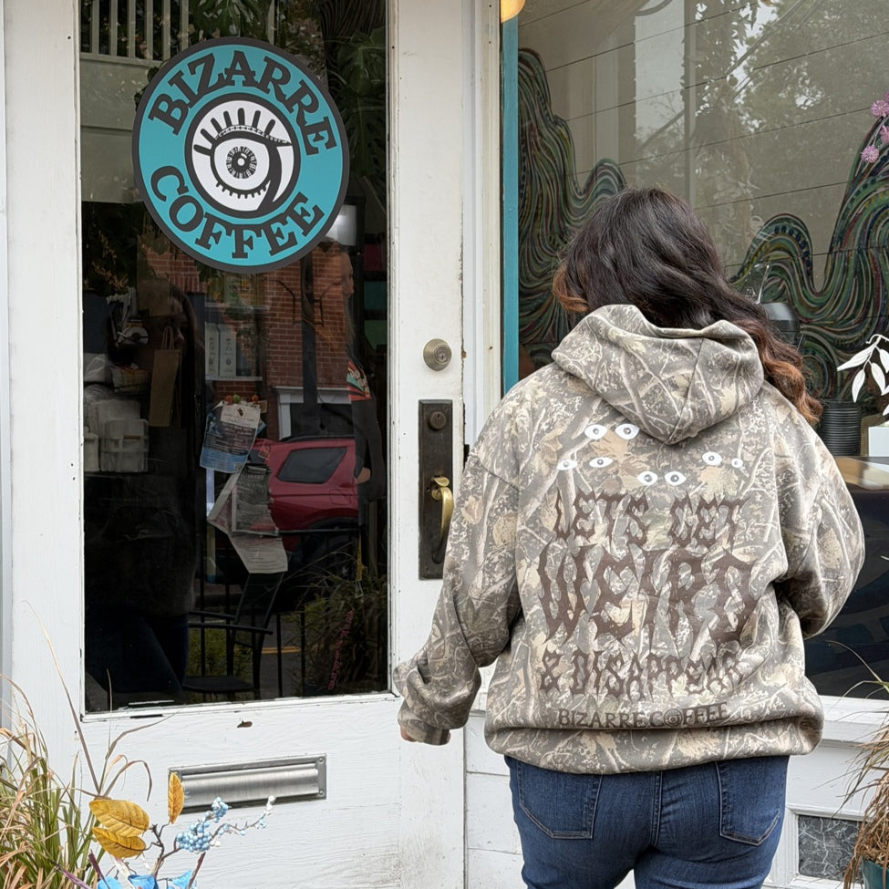 Person walking past a coffee shop named 'Bizarre Coffee' with a decorative sign.