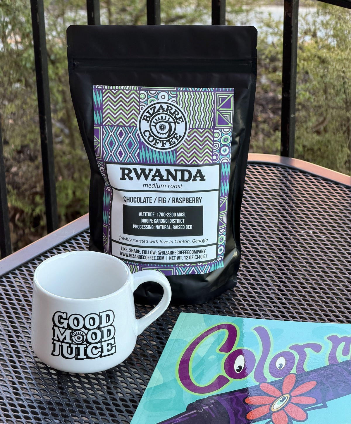 Coffee package, mug, and coloring book on a metal table outdoors